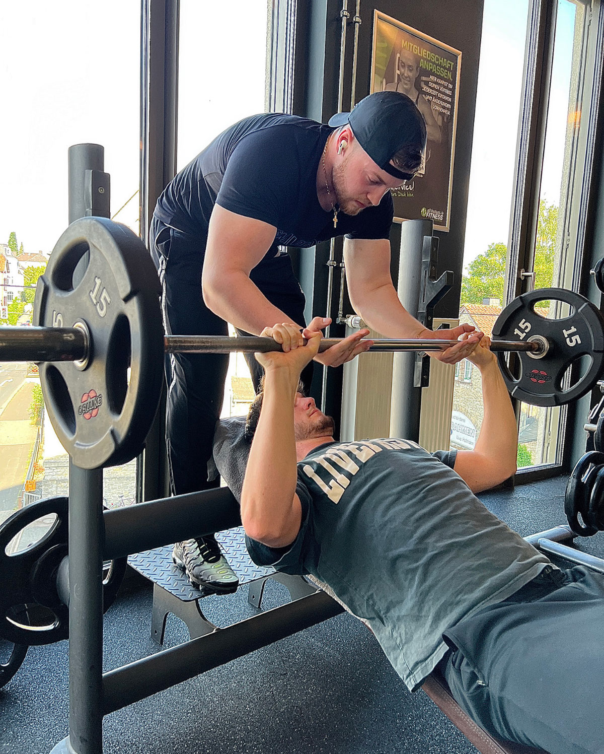 Der Coach hilft einem seiner Klienten beim Gewichtheben.